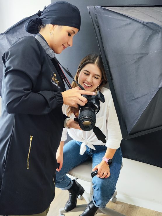 A dental professional shows a patient the results of her dental treatment using a camera, discussing the benefits of Carillas Cerámicas Biomiméticas.