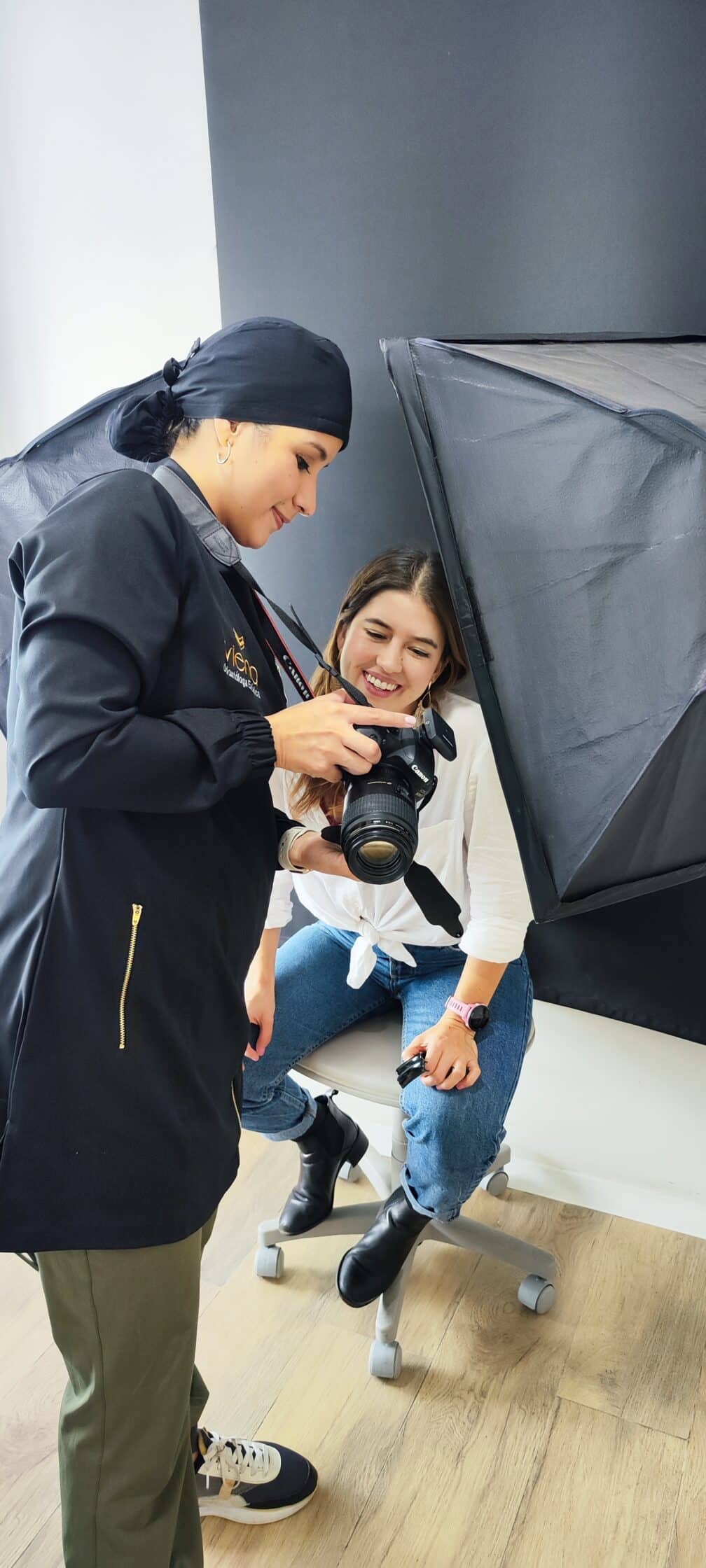 A dental professional shows a patient the results of her dental treatment using a camera, discussing the benefits of Carillas Cerámicas Biomiméticas.